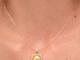 un gros plan d'une femme portant un collier en or orné d'un visage