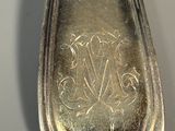 a silver spoon with a monogram on it sitting on a table