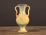 un vase jaune posé sur une table en bois, sur fond noir