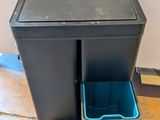 a black trash can and a blue trash can on the floor