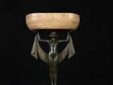 a bronze statue of a woman holding a bowl on her head
