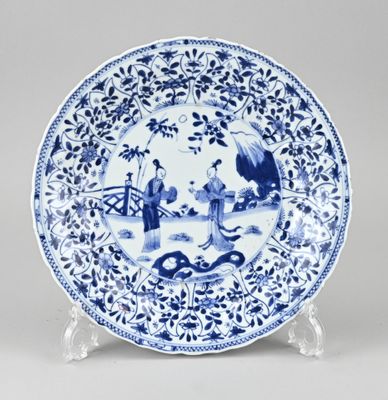 Assiette bleue et blanche représentant un homme et une femme dans un jardin