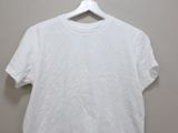 a white t - shirt hanging on a hanger in a room