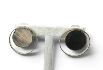 paire de boucles d'oreilles en argent et nacre, posées sur un présentoir blanc