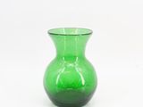 un vase en verre vert posé sur une surface blanche