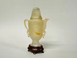 un vase en verre orné d'un visage, posé sur un socle