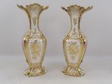 pair of gold and white vases sitting on a white surface