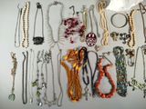 many necklaces and bracelets laid out on a table