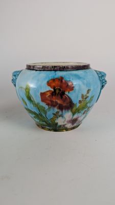 un vase bleu sur lequel est peinte une fleur