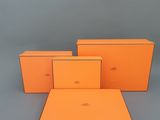 trois boîtes orange empilées les unes sur les autres sur une surface grise