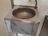 un lavabo dans un coin de la salle de bains, équipé d'un robinet en métal
