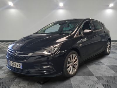 une voiture noire est garée dans une grande pièce au sol en damier