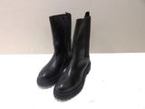 pair of black boots sitting on top of a white table