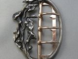 une image représentant une broche en argent ornée d'un oiseau et de fleurs