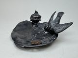a bird sitting on a leaf shaped dish with a bird on top of it