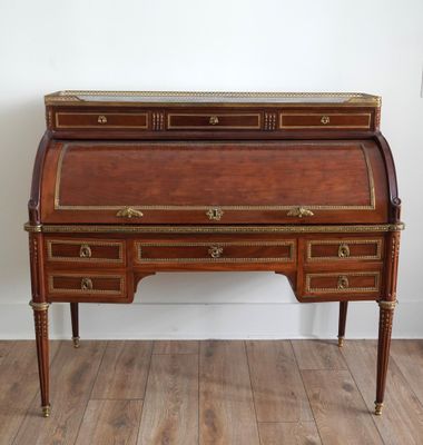 an antique writing desk with two drawers and gold trimmings