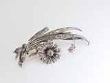 a close up of a silver broochle with flowers on it