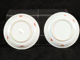 two white plates with red designs on them on a black surface