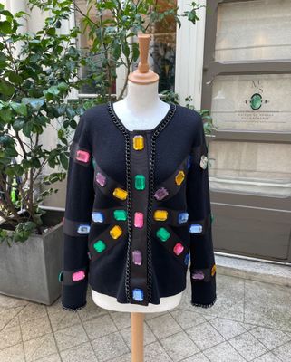 un cardigan noir orné de boutons multicolores, présenté sur un mannequin