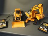 two remote controls and a toy bulldozer on a table