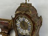 a clock that is sitting on the ground with a bird on it