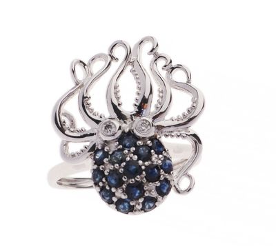 un gros plan sur une bague en forme de pieuvre ornée de pierres bleues et blanches