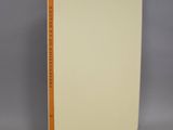 un livre blanc aux bords orange posé sur une surface grise