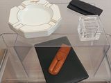 une table en verre sur laquelle se trouvent un étui à cigarettes et un cendrier en verre