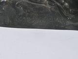 statue of a dog on a rock on a white surface