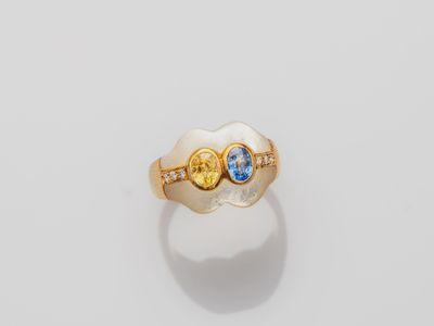 a close up of a gold ring with two blue and yellow stones