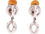 une paire de boucles d'oreilles argentées et orange sur fond blanc