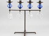 trois vases en verre bleu sont posés sur un support métallique muni d'un bougeoir