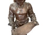 bronze statue of a man holding a scroll with writing on it