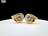 une paire de boucles d'oreilles en or et saphir bleu sur un fond blanc