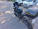 a black motorcycle parked in a parking lot next to a white van