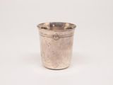 une tasse en argent posée sur une surface blanche