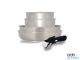 trois casseroles en acier inoxydable et une spatule sur fond blanc