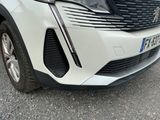 the front end of a white car parked on the side of the road