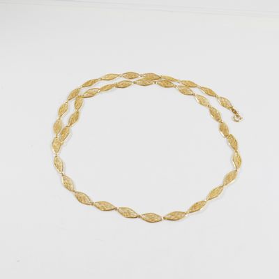 gros plan d'un bracelet en or sur une surface blanche