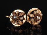 une paire de boucles d'oreilles en or ornées de perles sur un fond noir