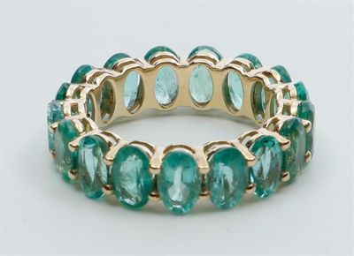 une image représentant une bague ornée de pierres vertes sur un fond blanc