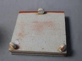 a small square piece of ceramic with a hole in the middle