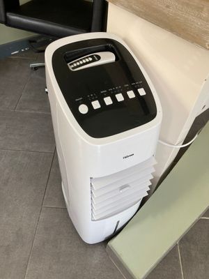 a small air conditioner sitting on the floor next to a chair
