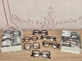 Plusieurs paires de lunettes sont posées sur une table devant un mur.