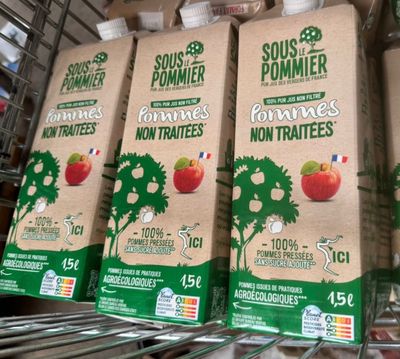 four cartons of fruit juice sit on a shelf in a grocery store