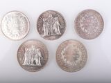 quatre types différents de pièces d'argent sur une surface blanche