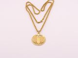 un collier en or avec un médaillon et une chaîne sur fond blanc