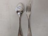 two forks and a spoon on a white table