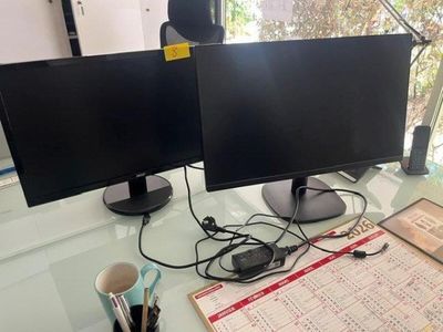 two computer monitors sitting on a desk with a cup of coffee