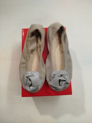 une paire de chaussures grises ornées de nœuds, posée sur une boîte rouge
